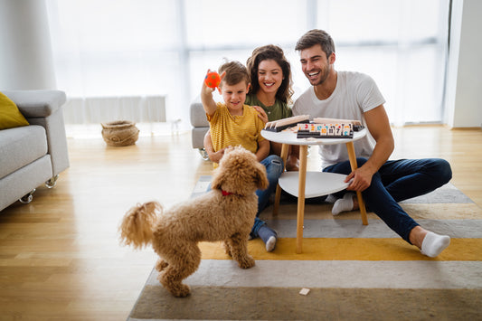 Happy family playing with dog near table